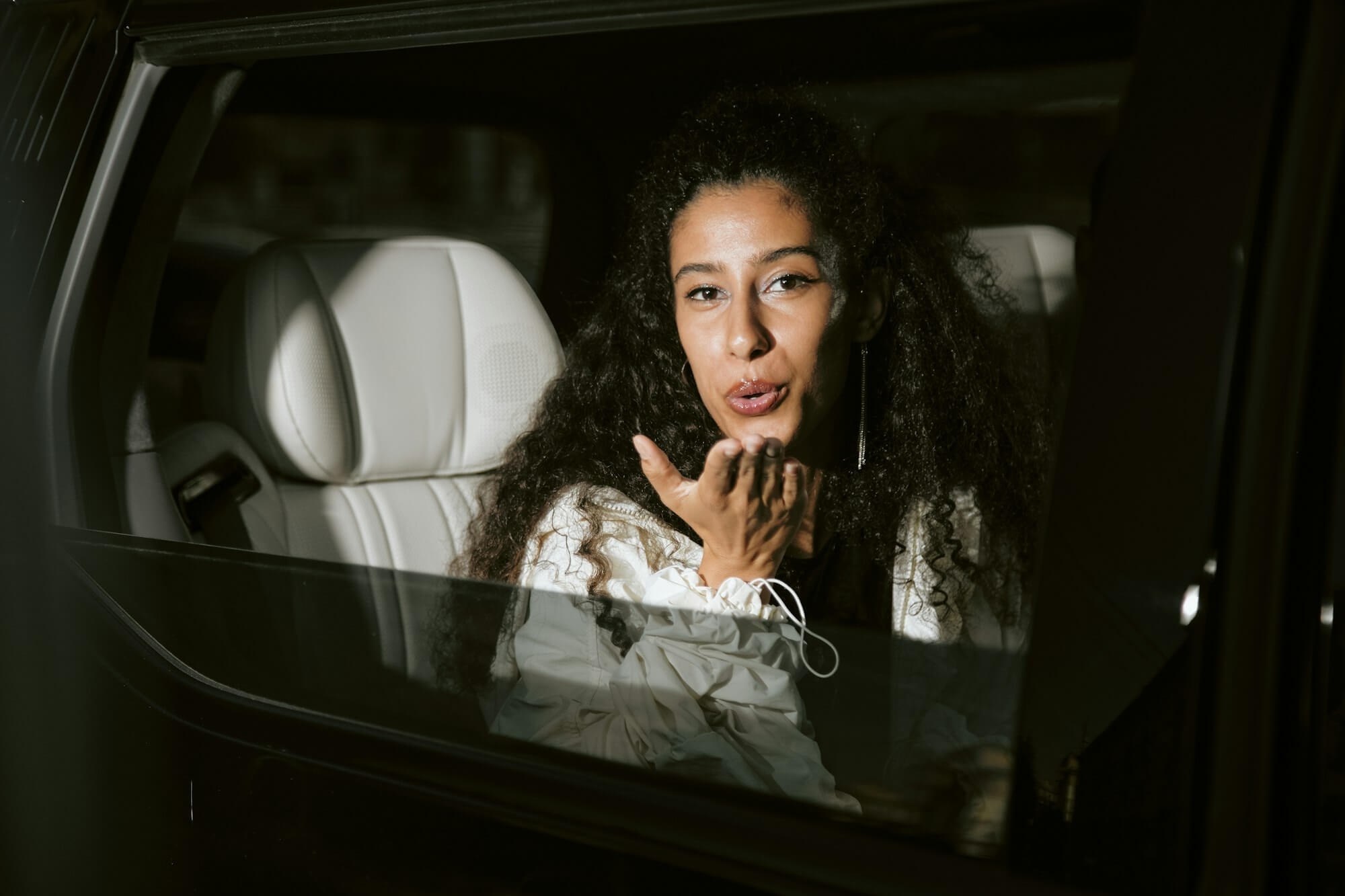 Portrait of Famous Woman Blowing Kiss Sitting in Back Seat of Car
